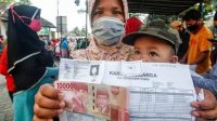 Warga menerima bantuan sosial (Bansos) tahap dua Provinsi Jawa Barat, di Kelurahan Harapan Jaya, Cibinong, Kabupaten Bogor, Kamis (23/7/2020). (Foto: Antara)