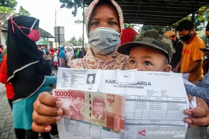 Warga menerima bantuan sosial (Bansos) tahap dua Provinsi Jawa Barat, di Kelurahan Harapan Jaya, Cibinong, Kabupaten Bogor, Kamis (23/7/2020). (Foto: Antara)